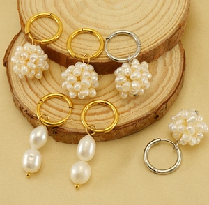 Detailed view of 18k gold pearl earrings on rustic wood slice with baroque design