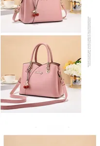 Detail of pink handbag featuring a gold logo and a cute cherry charm accessory