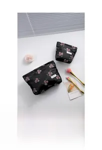 Macro detail of floral jacquard embroidery on black satin fabric with H&R BAG logo tag