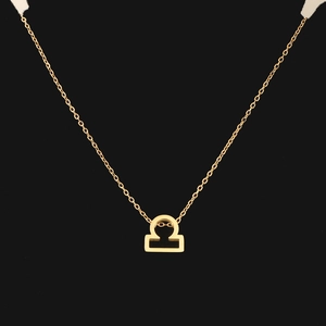 Close-up of golden necklace with Libra zodiac sign pendant on a black background