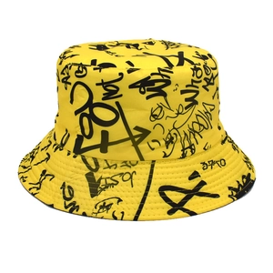 Detail of yellow bucket hat featuring black graffiti letter prints and cotton texture