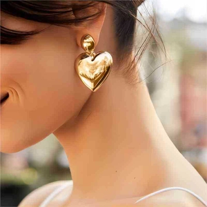 Boucles d'oreilles cœur en acier inoxydable doré 18K portées par un mannequin