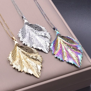 Macro shot of three leaf-shaped pendants in gold, silver, and rainbow on a jewelry box