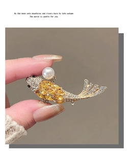Detailed close-up of a golden koi fish brooch with yellow crystals and a white pearl