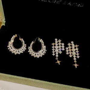 Elegant gold earrings set with pearls and star pendants on a black velvet jewelry box