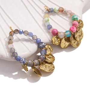 Detail of colorful bohemian beaded charms with gold teardrop pendants on a white shell