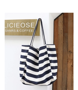 Detail of a casual black and white striped canvas tote bag hanging in a minimalist cafe setting