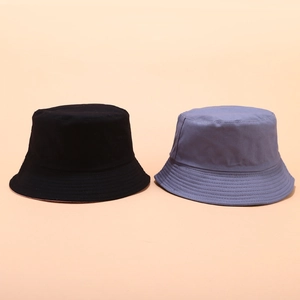 Detail of black and grey-blue reversible bucket hats showing neat stitching and cotton texture
