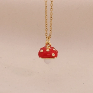 Macro-opname van schattige rode paddenstoel hanger aan gouden ketting met witte steel
