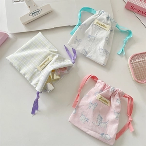 Macro shot of cotton drawstring bags for cosmetics with cat patterns on a clean desk
