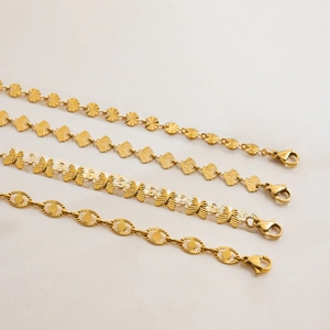Dettaglio di quattro bracciali in acciaio inossidabile dorato con maglie a foglia e farfalla
