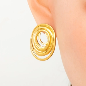Macro shot of gold spiral textured hoop earrings in S925 silver on a model's ear