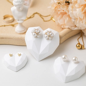 Elegant heart-shaped jewelry display stand with gold heart earrings and pearl studs