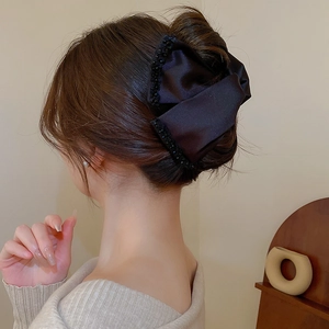 Close-up of black satin bow hair claw with sparkling sequins on elegant hairstyle