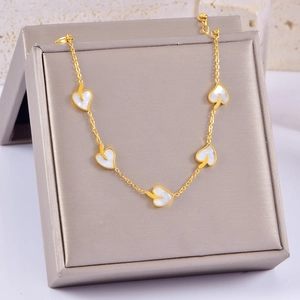 Detail of a gold necklace with white mother of pearl leaf pendants on a jewelry display box