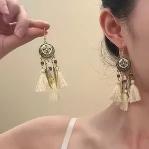 Detail of bohemian ivory tassel earrings with vintage gold metal and wooden beads