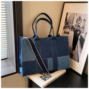 Detail of color-block denim tote bag with wide fabric shoulder strap and sturdy handles