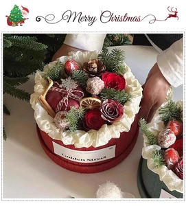 Close-up of a Christmas floral gift box with red roses, pine cones, and cinnamon sticks