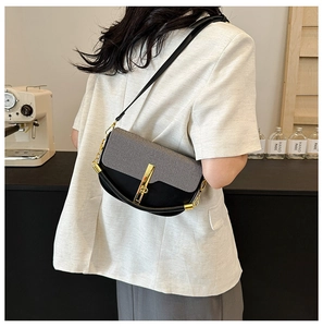 Detail of color-block shoulder bag with gold hardware and chain strap shown in cafe setting