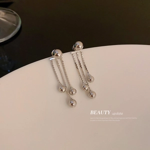 Modern silver bead tassel earrings on white display tray with elegant lighting