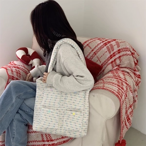 Close-up of plush tote bag with colorful plaid knit patterns and decorative candy buttons