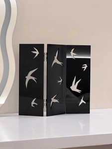 Detail of black acrylic folding screen with silver swallow cutouts and metal hinges