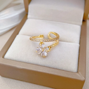 Detailed close-up of golden clover ring with sparkling zircons in a jewelry box