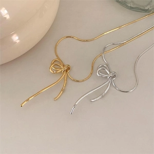 Detailed view of 925 sterling silver bow knot pendant on delicate snake chain necklace