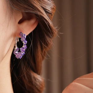 Close-up of elegant purple faceted crystal hoop earrings worn on a model's ear