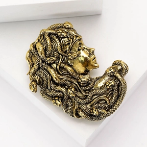 Macro view of vintage gold Medusa head brooch with detailed silhouette and textured finish