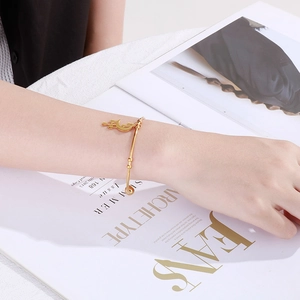 Detailed close-up of a gold celestial bangle with moon and star charms on a woman's wrist