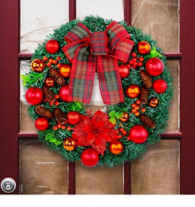 Close-up of a festive Christmas wreath with red bows and gold ornaments on a wooden door