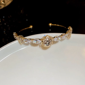 Macro shot of gold-plated bangle with hollow rose pattern and marquise-cut zircon stones