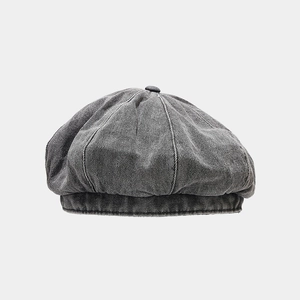 Detailed close-up of a vintage washed denim newsboy cap with grey texture and top button