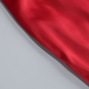 Gros plan sur un tissu en satin rouge foncé montrant une texture lisse et brillante