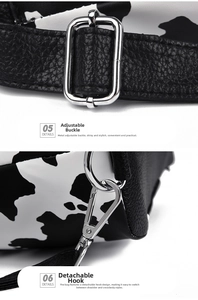 Close-up of cow print shoulder bag with silver adjustable buckles and detachable hooks