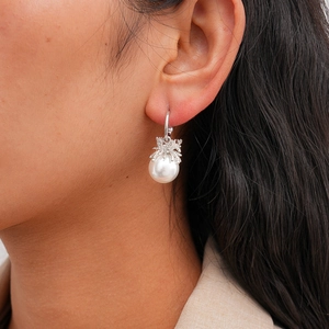 Close-up of elegant C-shaped faux pearl earrings worn by model with silver details
