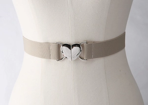 Gros plan sur la ceinture élastique beige avec boucle argentée en forme de cœur