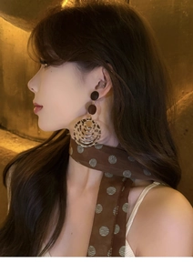 Close-up of leopard print layered hoop earrings and a brown polka dot neck scarf