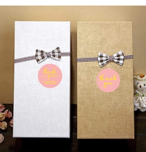 Close-up of pink 'thank you' stickers on gift boxes with checkered ribbons and a small bear