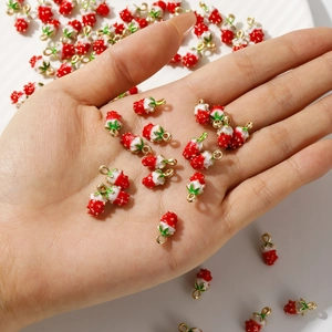 Detailed close-up of 3D strawberry alloy charms with red enamel finish for jewelry making