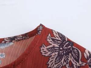 Close-up of rust red ethnic floral print fabric with vertical texture and neat stitching