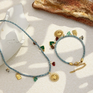 Détail d'un ensemble collier tressé bohème avec pendentif soleil en or 18K et breloques