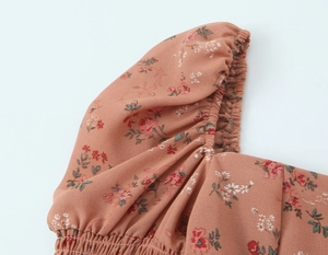 Détail des manches bouffantes fleuries avec poignets élastiques et mousseline rouge brique