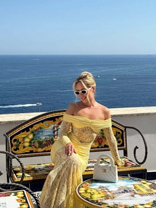 Detail of yellow floral lace off-shoulder maxi dress with sheer long sleeves and texture