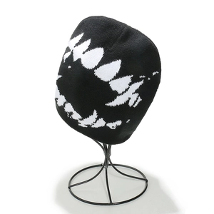 Detail of black knit beanie with white sharp teeth pattern on a metal display rack