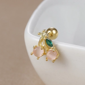 Macro view of cherry studs with pink stones and gold base on a white ceramic bowl edge