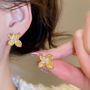 Detailed close-up of golden flower stud earrings with sparkling white zircon centers