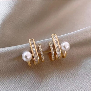Macro detail of gold-plated pearl tassel earrings with shimmering pavé zircon stones