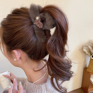 Detail of brown plush hair claw clip with leopard heart and rhinestone on a woman